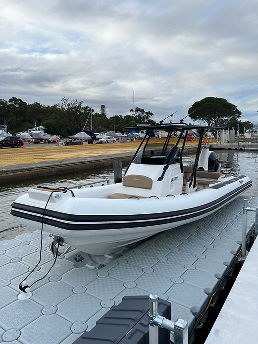 A boat is securely docked at a floating dock in a marina, surrounded by calm waters and scenic views.