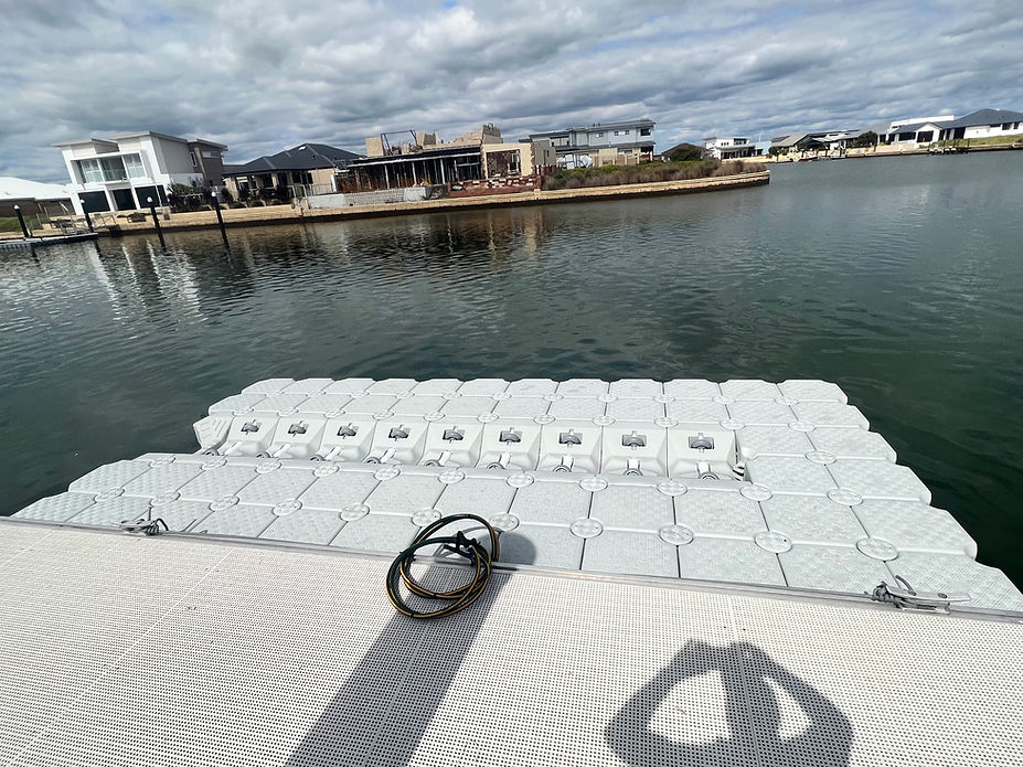 A floating boat dock featuring a white surface and a white dock mat, providing a clean and inviting space for vessels.