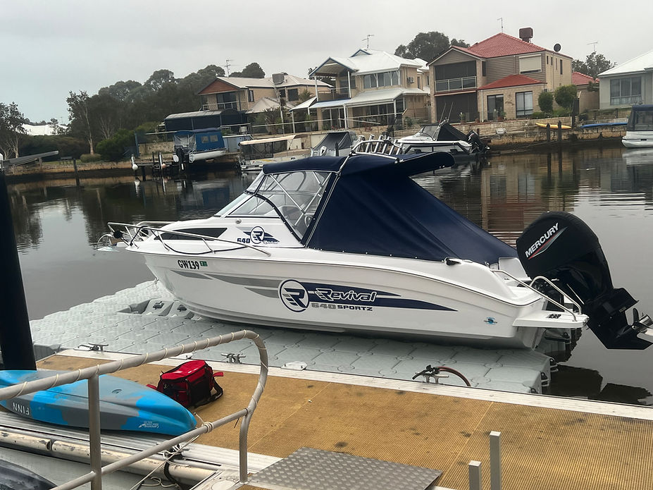 A boat is securely docked at a floating dock, accompanied by a boat trailer nearby.