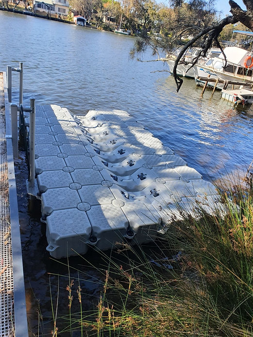A floating dock featuring multiple large white bags arranged neatly on its surface, surrounded by water.