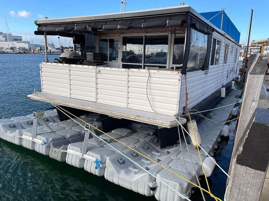 A houseboat is securely moored at a floating dock, surrounded by calm waters and a serene atmosphere.
