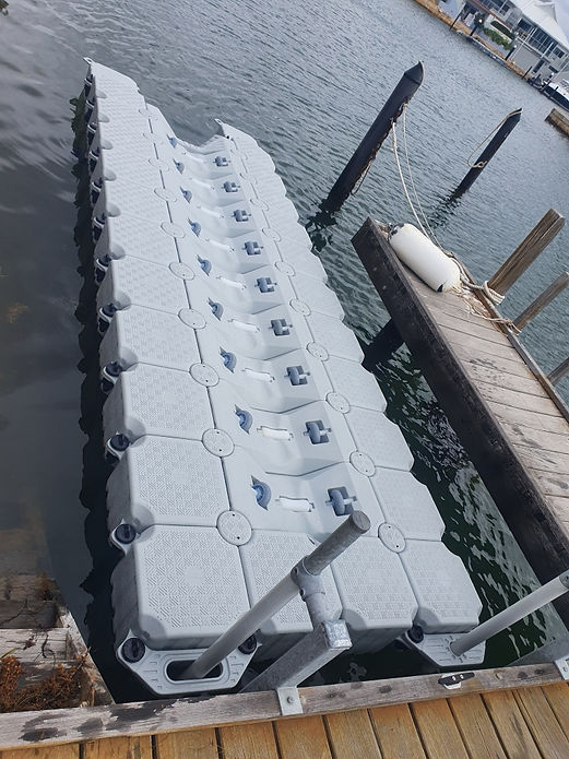 A large floating dock featuring several water jugs arranged neatly on its surface, surrounded by calm water.