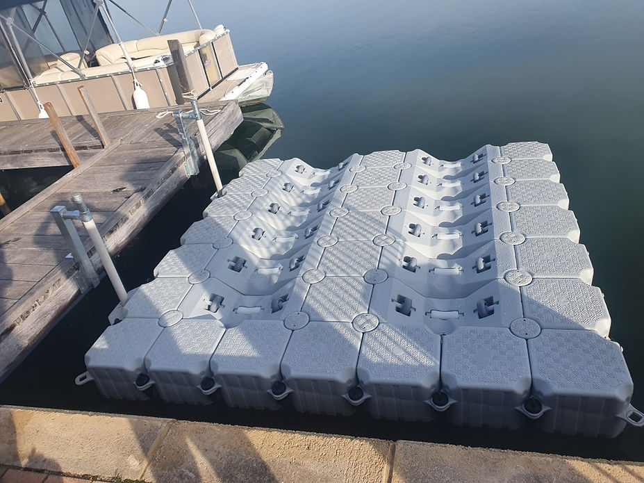 A floating dock featuring several large white containers arranged neatly on its surface, set against a calm water backdrop.