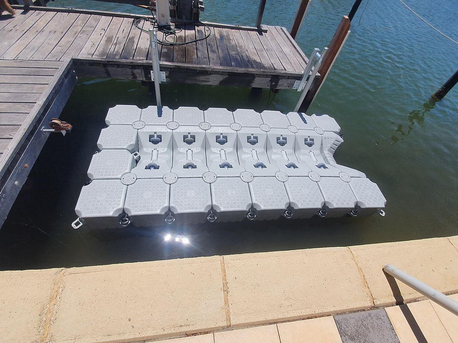 A floating dock featuring a boat moored alongside, surrounded by calm waters and a clear sky.