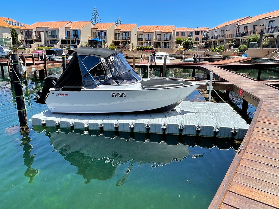A boat is securely docked at a floating dock in front of a charming house, surrounded by serene waters.