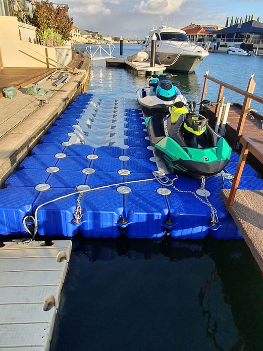 A jet ski secured to a floating dock alongside a boat, showcasing a serene waterfront scene.