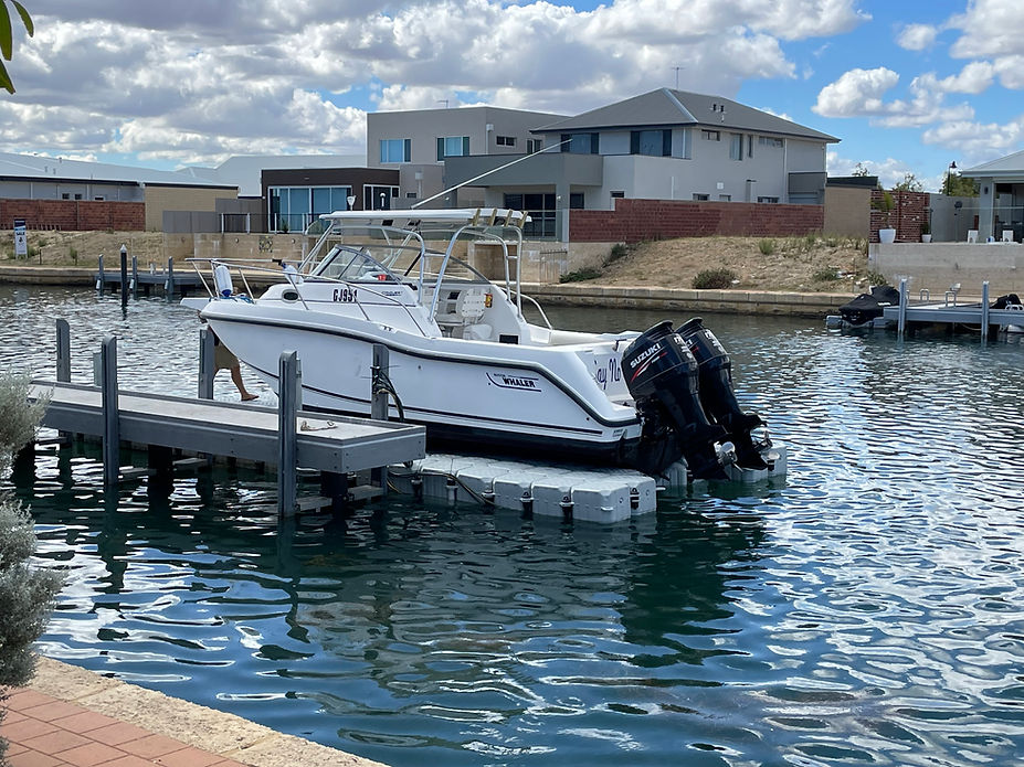 A boat is securely docked at a floating dock on a serene body of water, reflecting the calm surroundings.