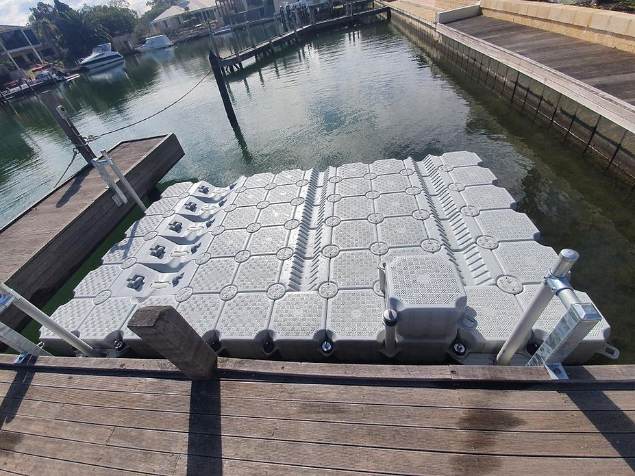 A floating dock with several water jugs arranged neatly on its surface, surrounded by calm water.