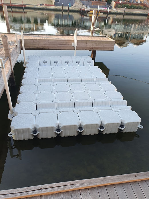 A floating dock featuring several white boxes arranged neatly on its surface, surrounded by calm water.