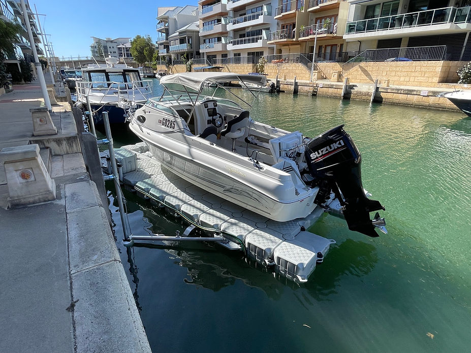 A boat is securely docked at a floating dock in front of a building, showcasing a serene waterfront scene.