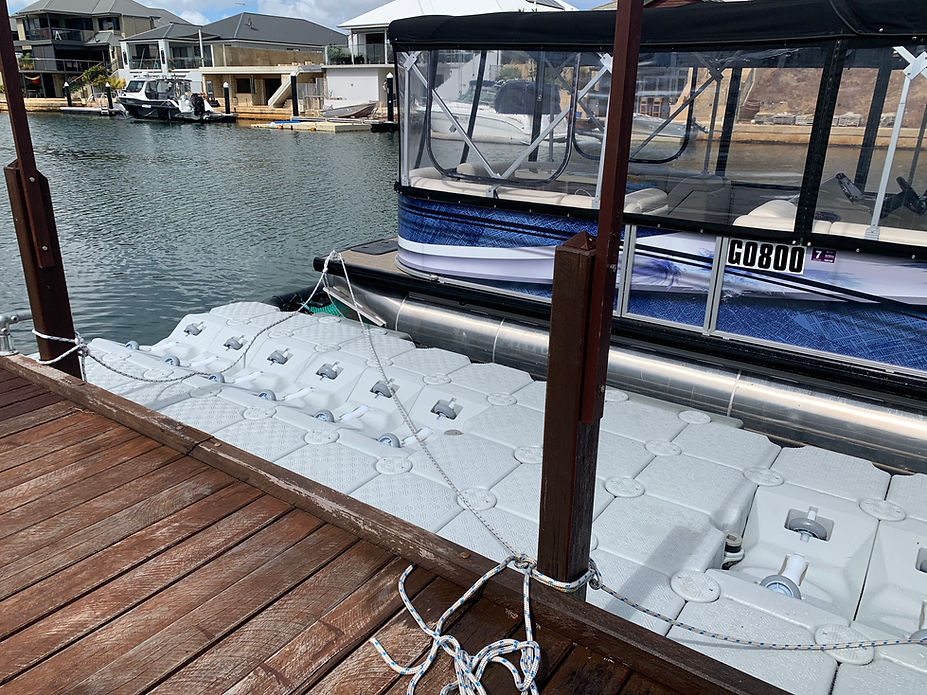 A large boat with an expansive deck is moored at a floating dock, showcasing its impressive size and design.