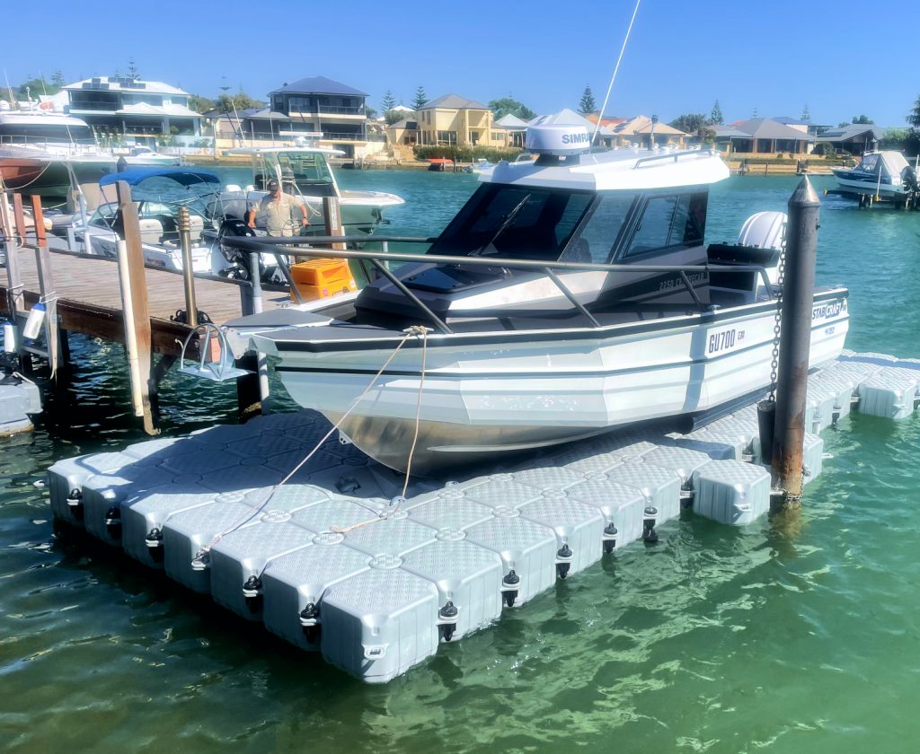 A boat is securely docked at a floating dock, gently resting on the calm water's surface.