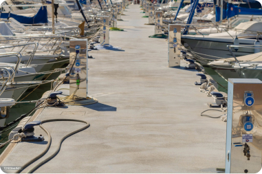A row of boats docked at a floating marina, surrounded by calm waters and a clear blue sky.