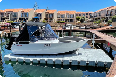 A boat is securely docked at a floating dock in front of a charming house, surrounded by serene waters.